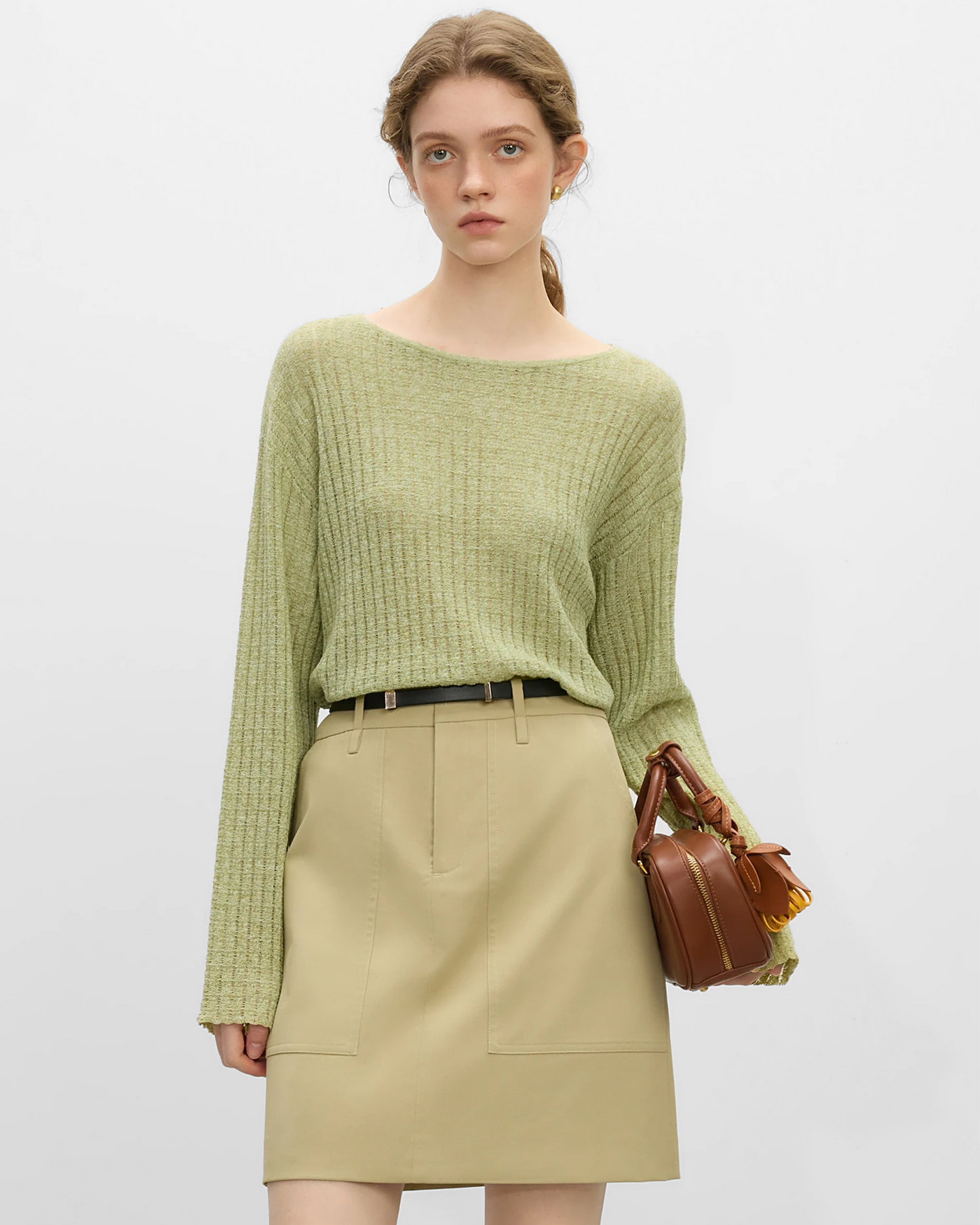Mujer luciendo un top de lino natural en color verde claro con falda beige y bolso marrón