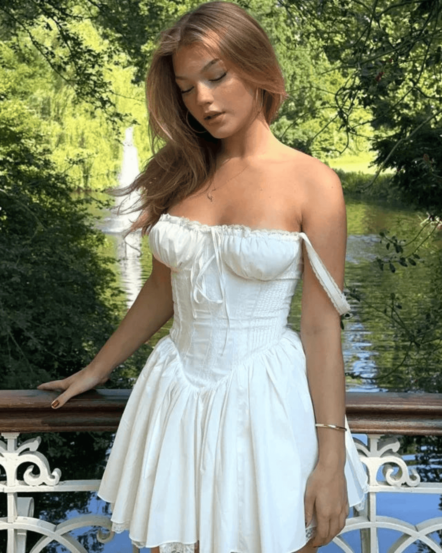 Modelo luciendo un vestido corsé blanco elegante en un entorno natural con un fondo de agua