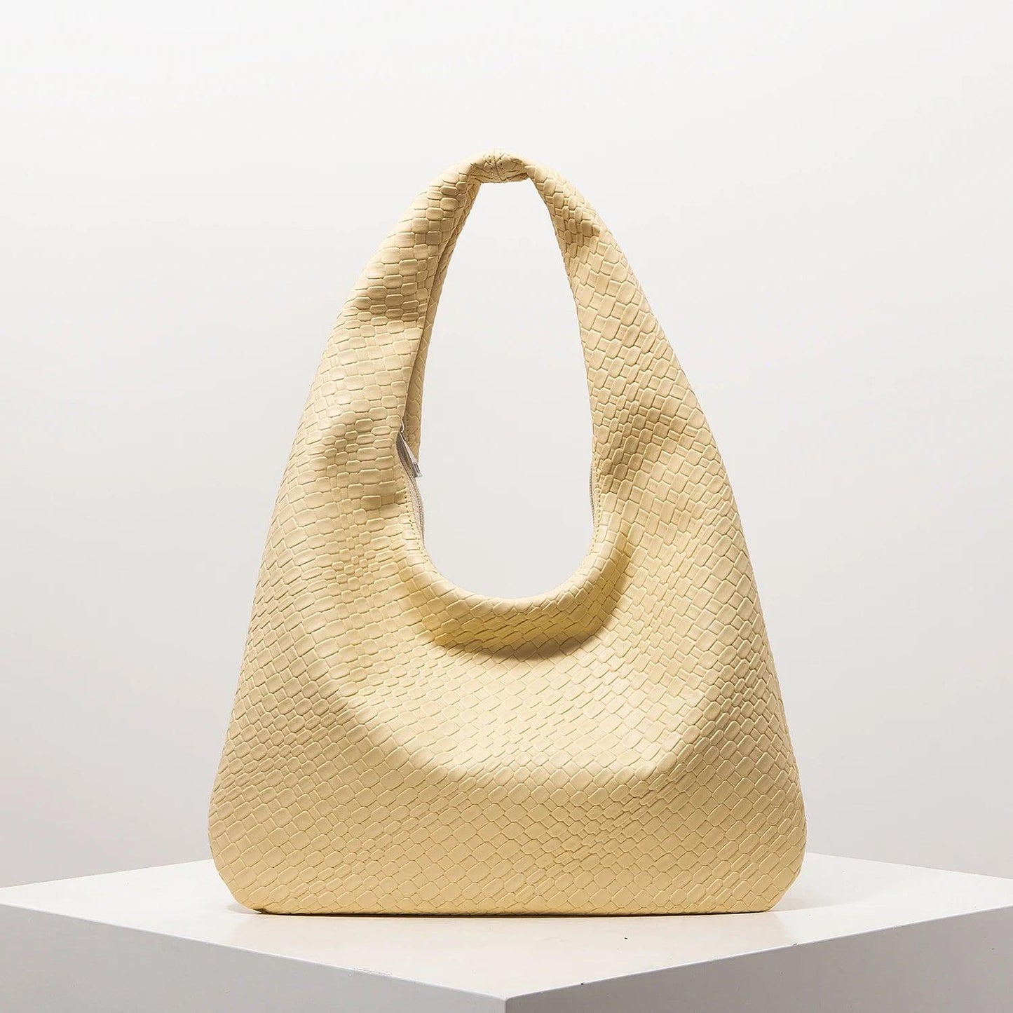 Bolso media luna trenzado en color amarillo claro, ideal para outfits casuales y elegantes