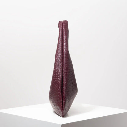 Bolso media luna trenzado en color burdeos, con diseño elegante y forma estilizada