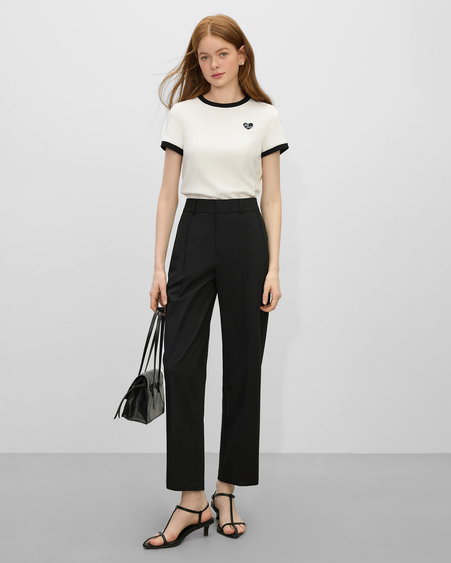 Mujer con pantalones traje grises mujer y camiseta blanca con detalles en negro, de Grevano