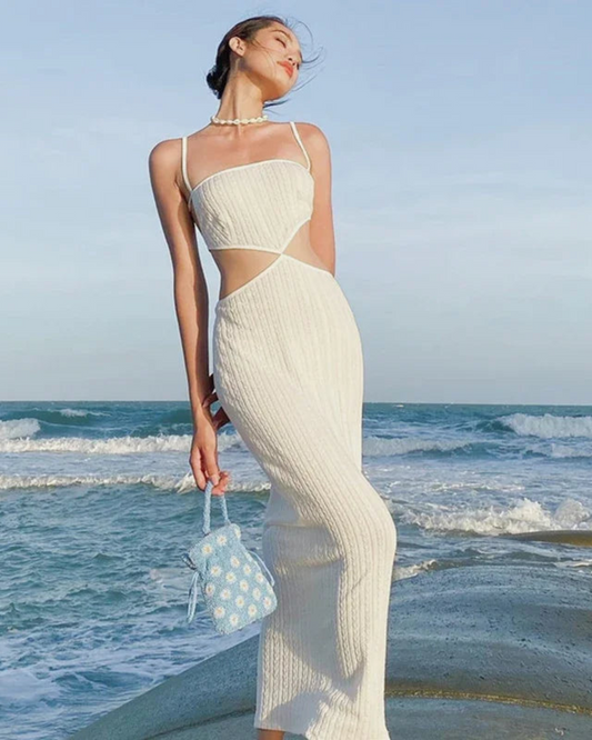 Mujer con vestido maxi playa blanco de Grevano junto al mar con bolso azul pequeño