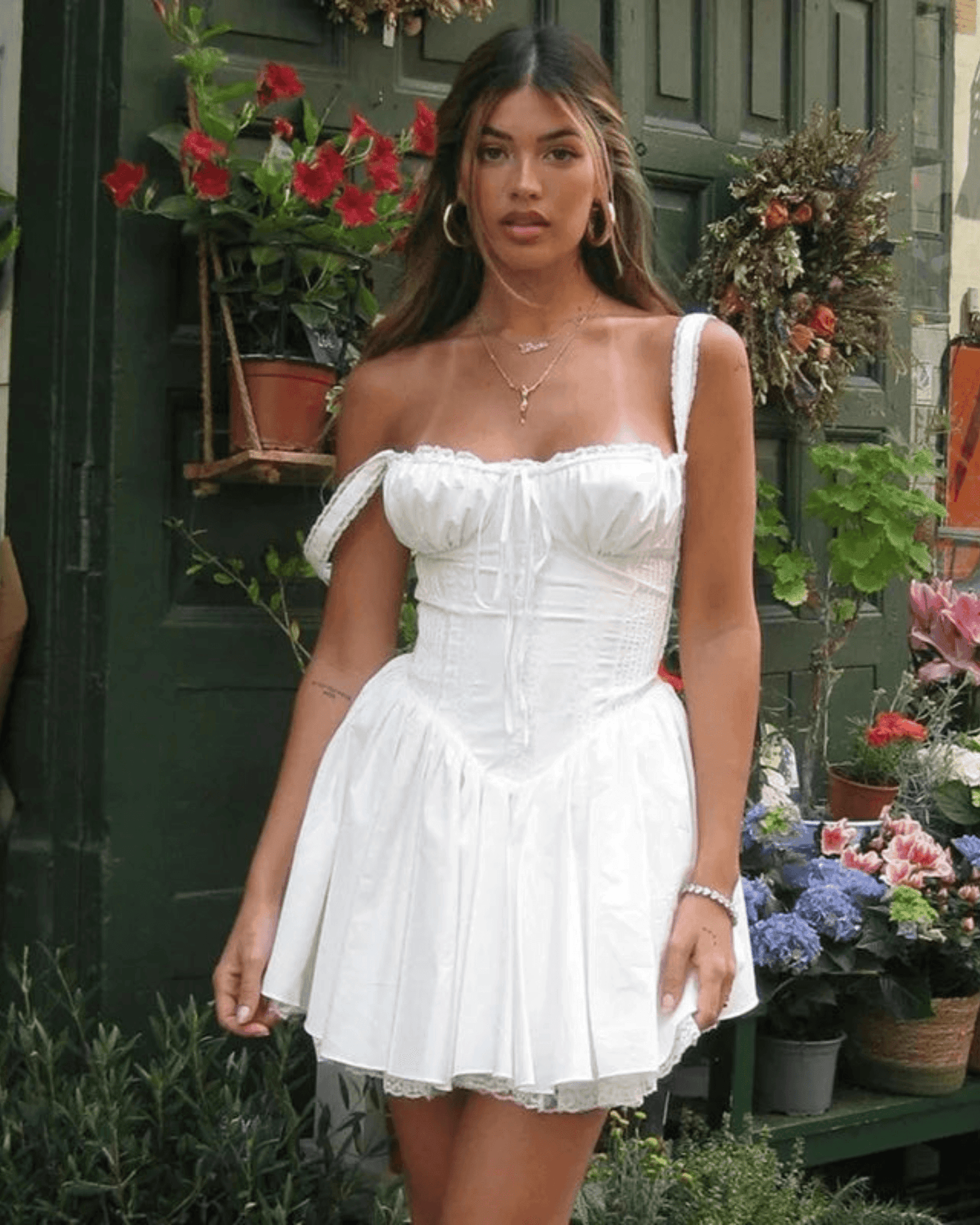 Mujer con vestido corsé blanco elegante con detalles de encaje y tirantes en un entorno floral