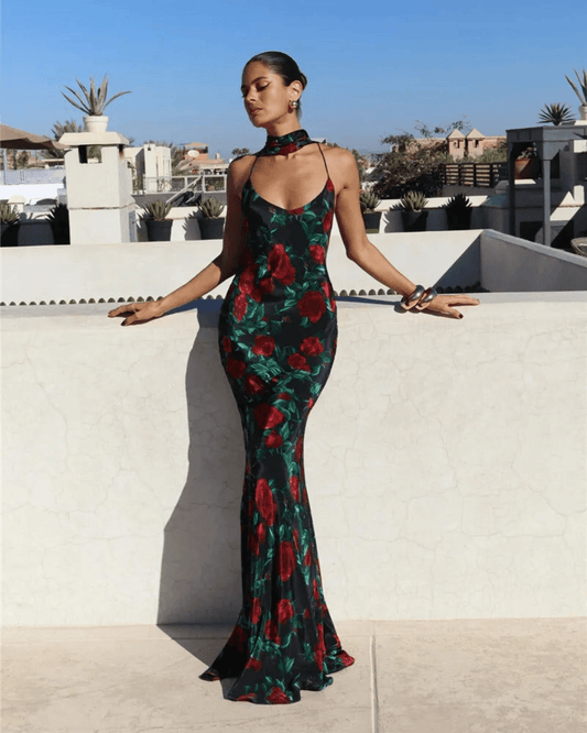 Mujer usando un vestido halter de gala elegante con estampado de flores rojas y fondo verde